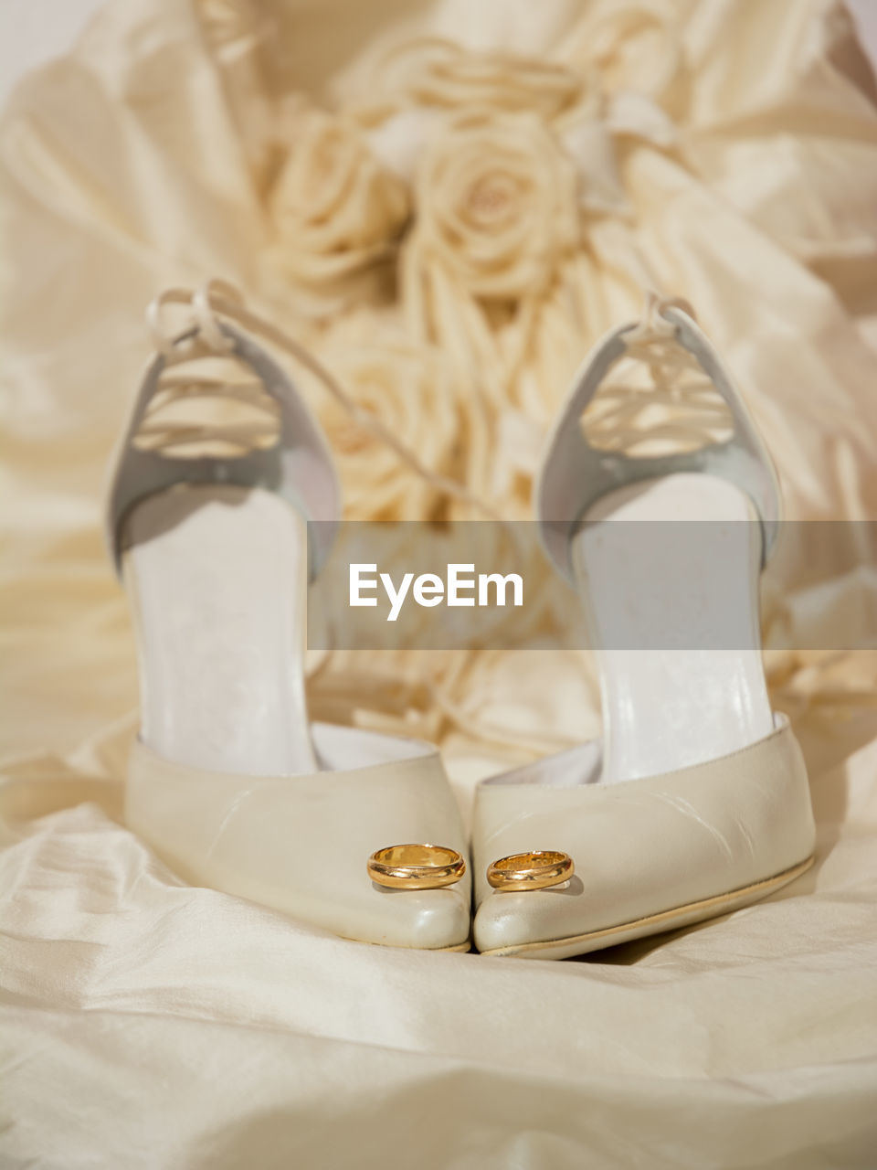 Close-up of wedding rings on high heels and dress