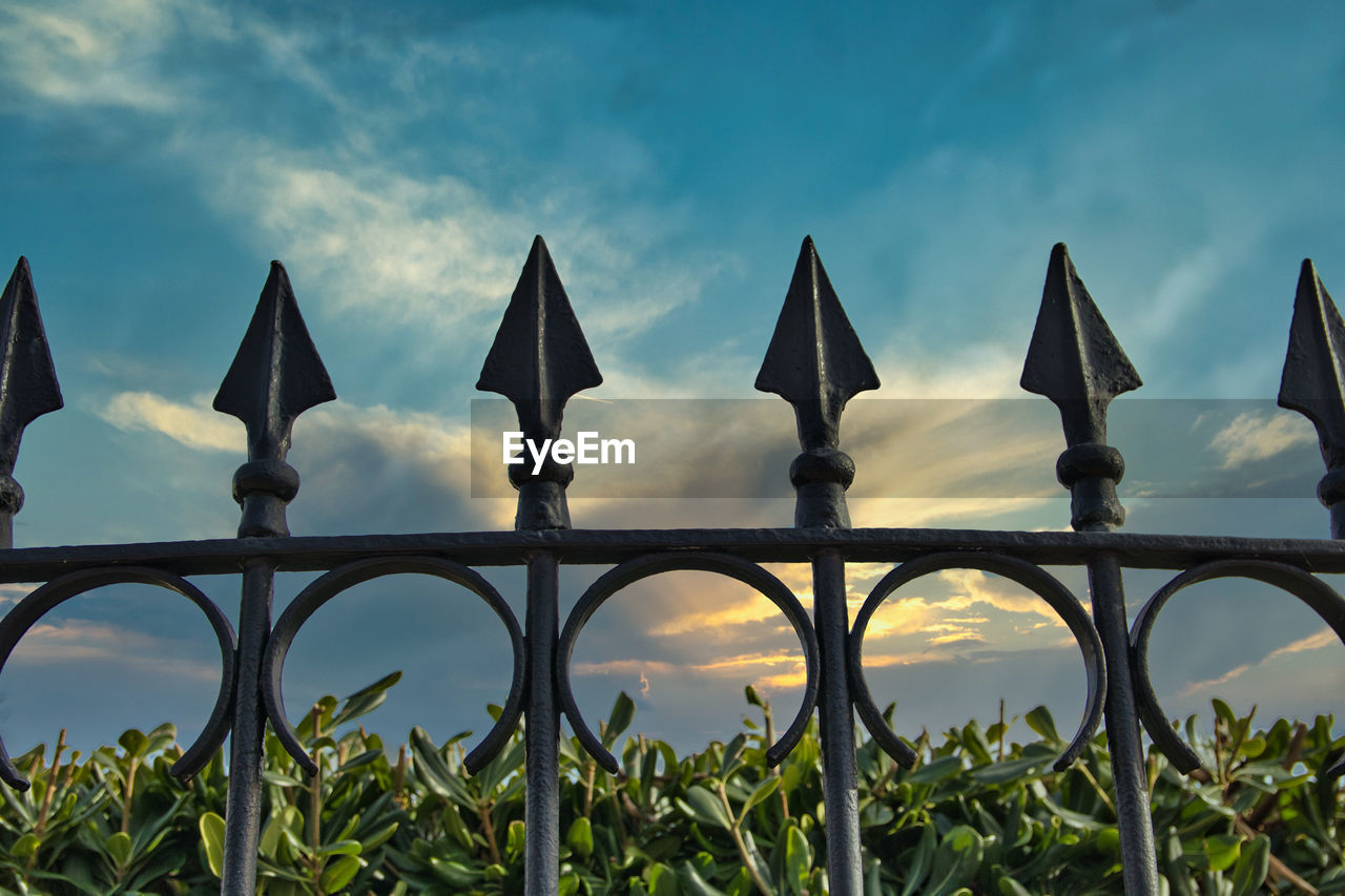 Low angle view of metal fence against sky