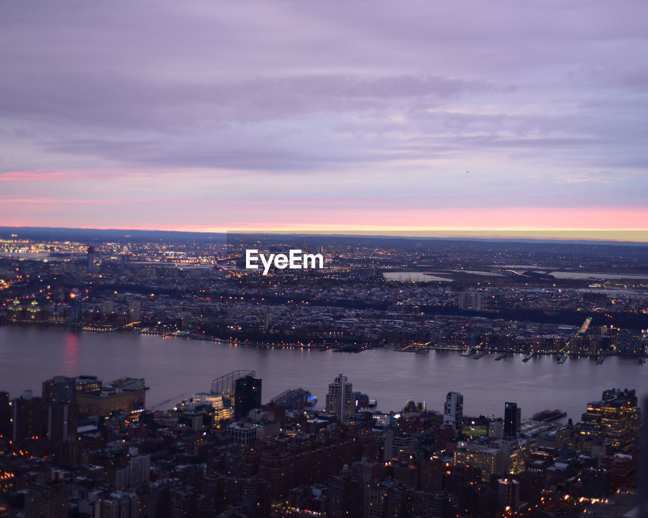 Aerial view of east river amidst building against cloudy sky at sunset