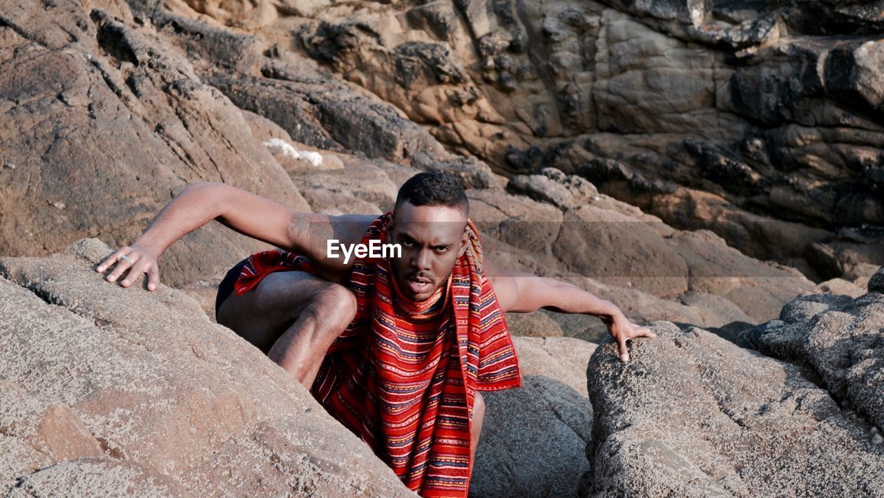 YOUNG WOMAN STANDING ON ROCK AT SHORE