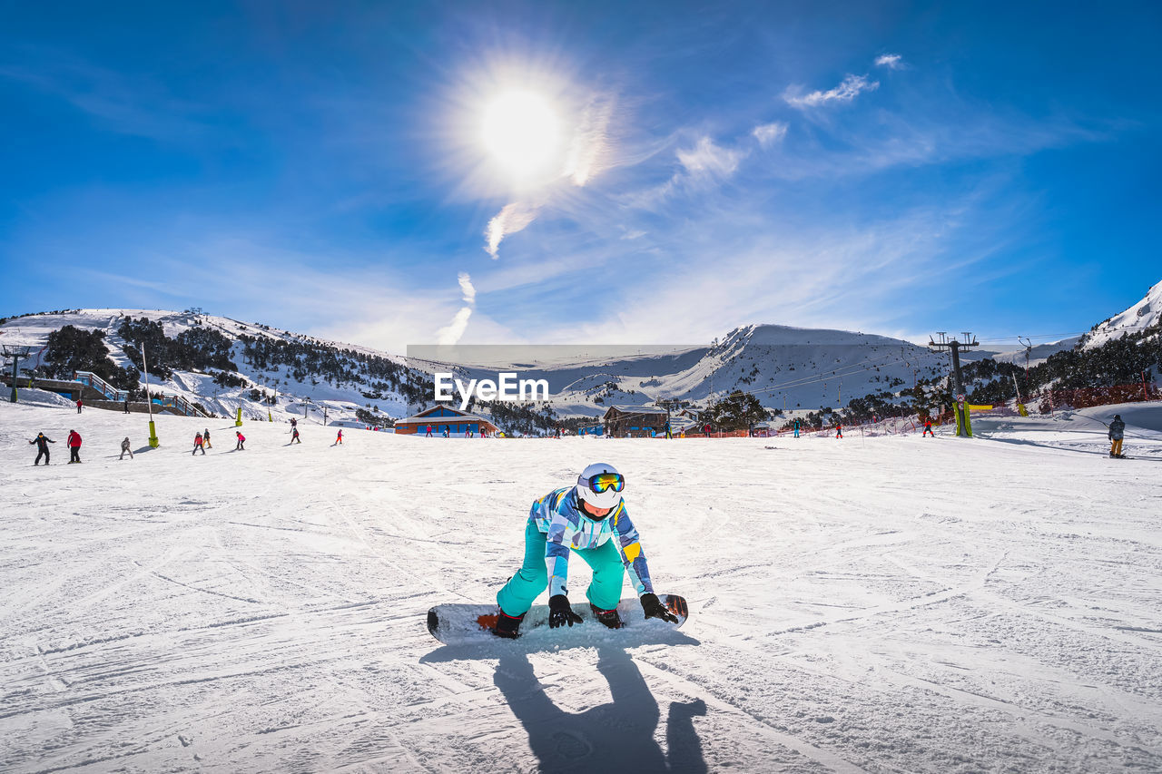 Woman, falling down when learning how to ride on a snowboard andorra