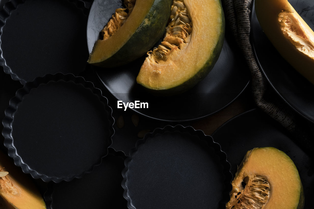 Pieces of sliced pumpkin on the dark table with dark dishes