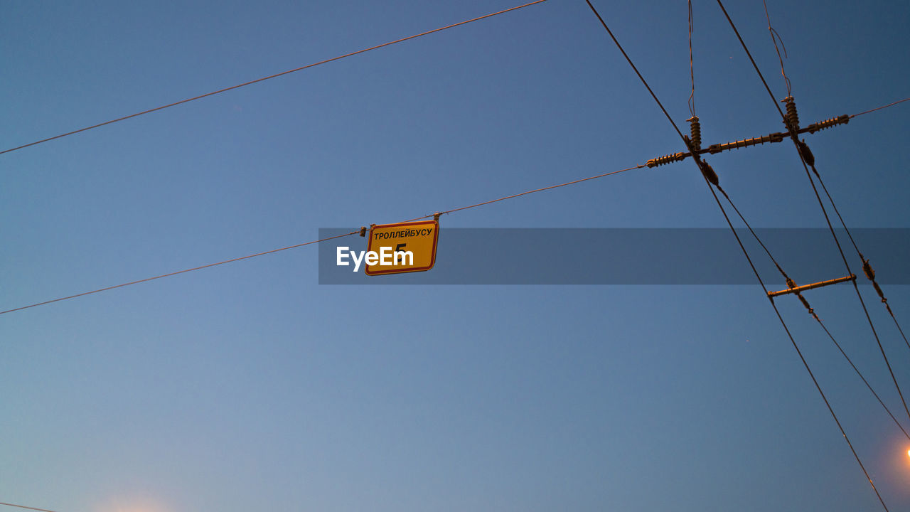 Low angle view of power lines against clear blue sky