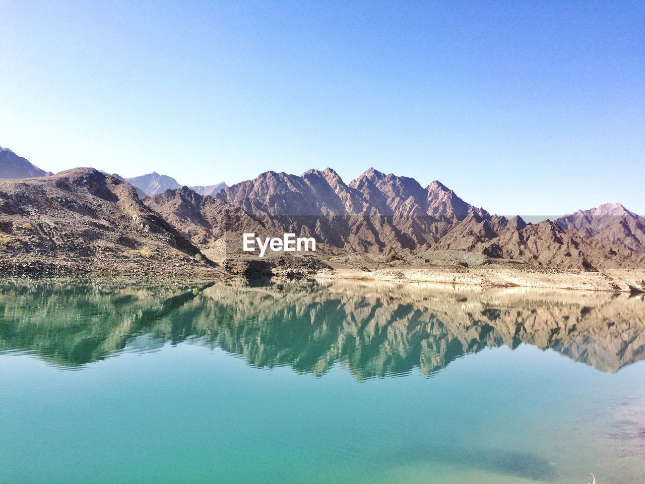 Reflection of mountains in lake against clear blue sky