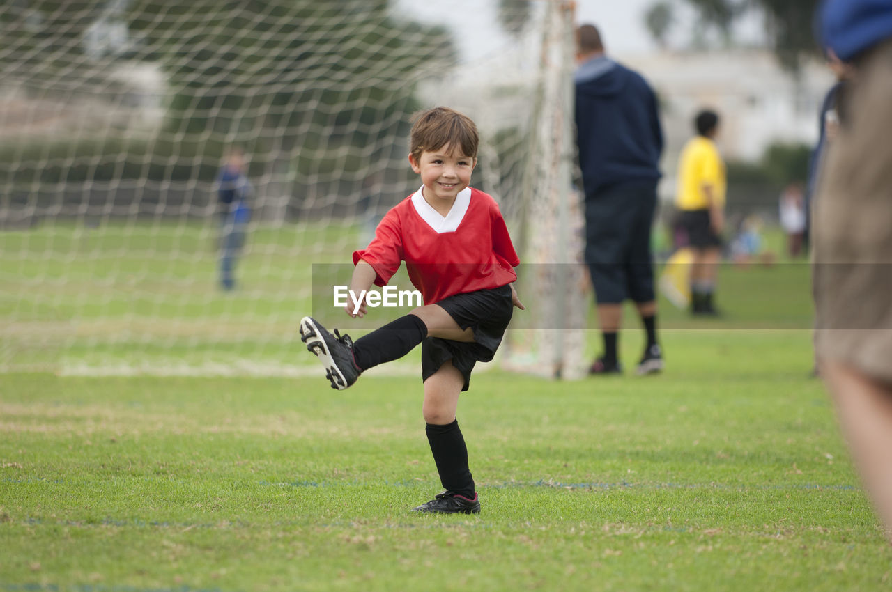 Young boy with big smile kicking an imaginary soccer ball