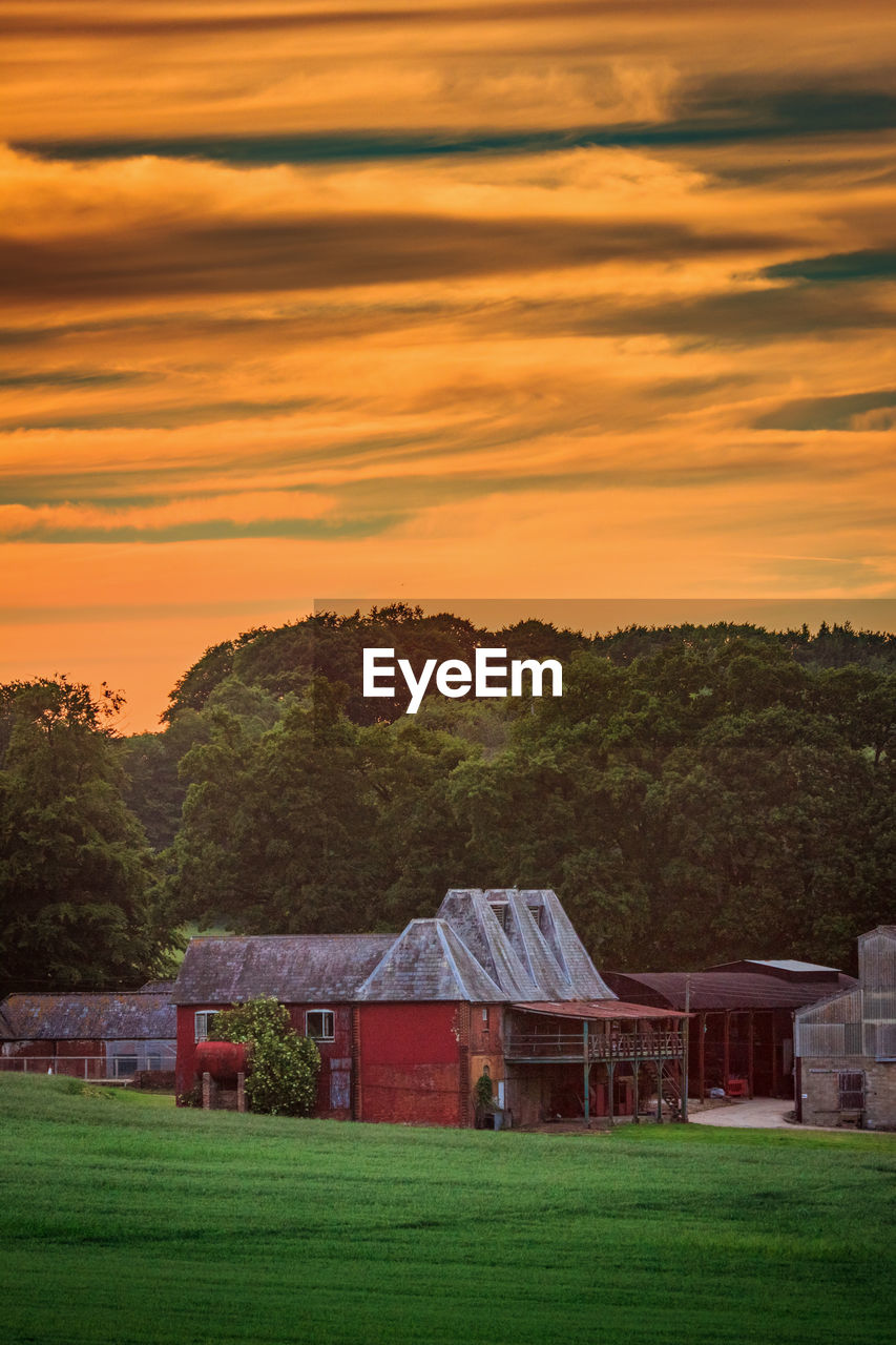 HOUSE ON FIELD AGAINST ORANGE SKY