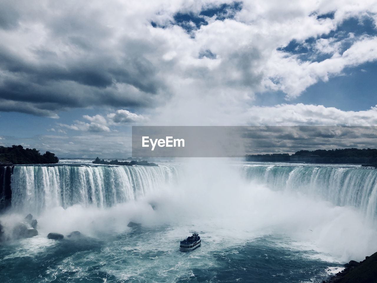 View of waterfall against cloudy sky