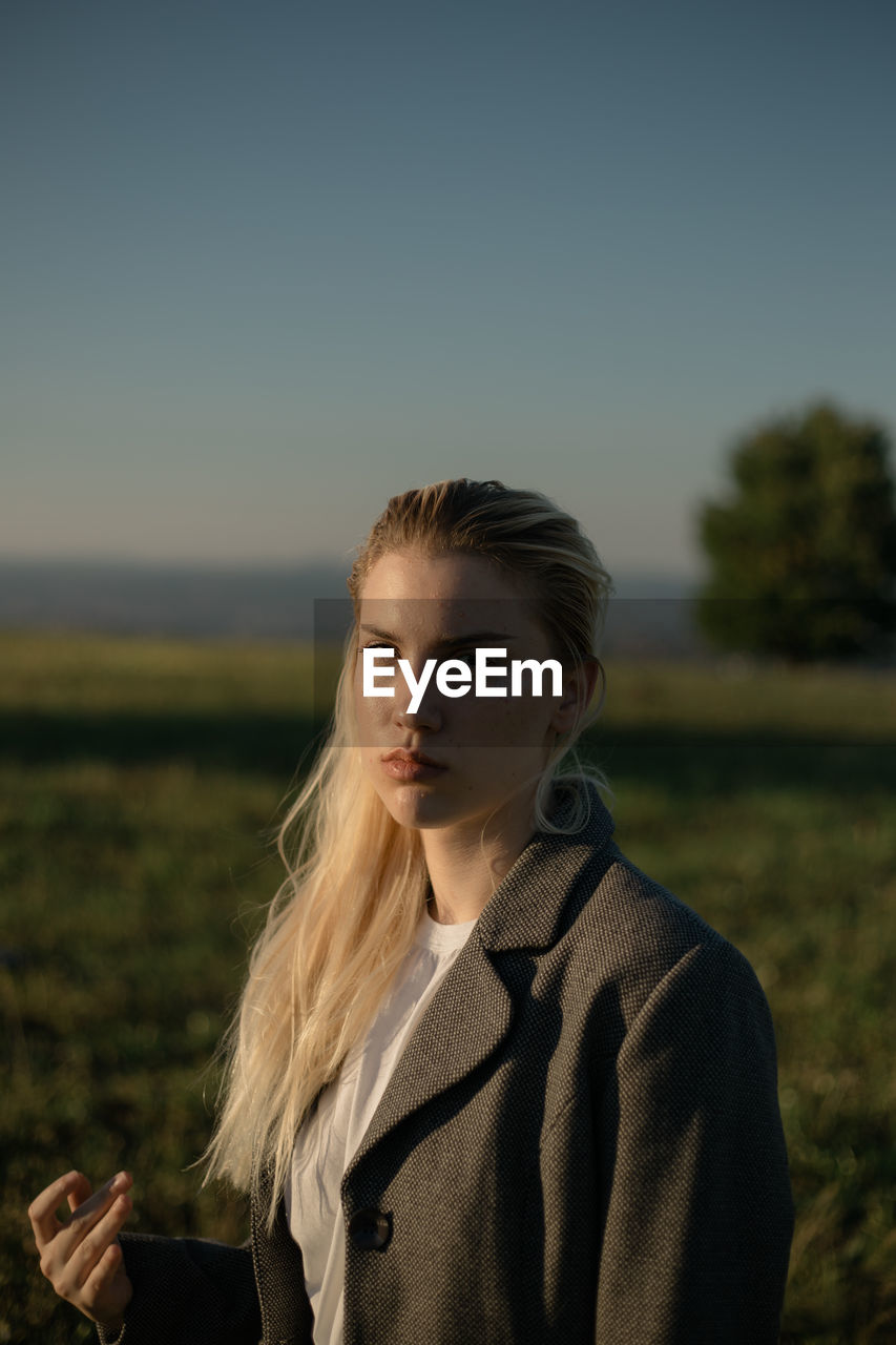 Portrait of woman standing on field against clear sky