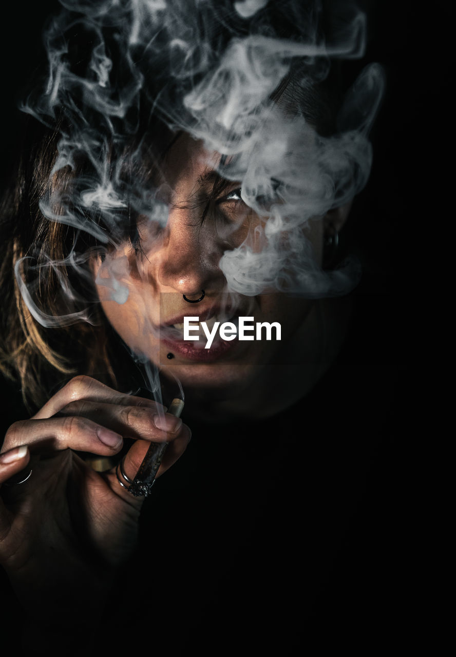 Portrait of woman smoking cigarette on black background