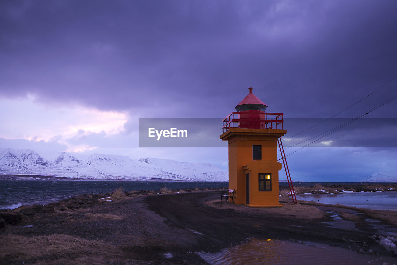 Orange lighthouse at the ocean at night, iceland