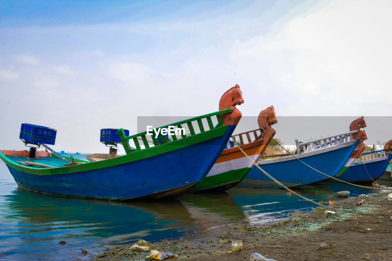 Boat moored on beach against sky