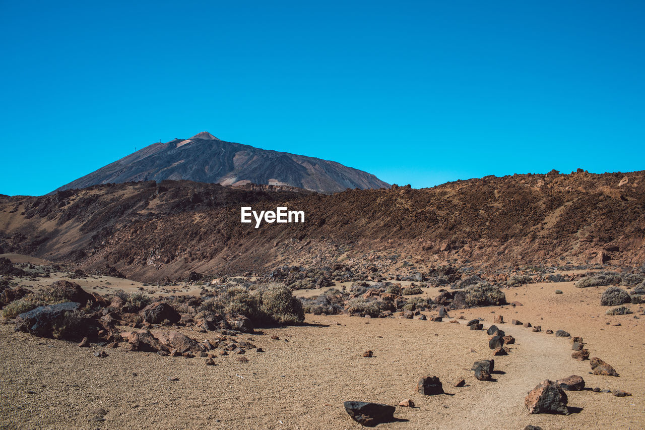 Scenic view of desert against clear blue sky