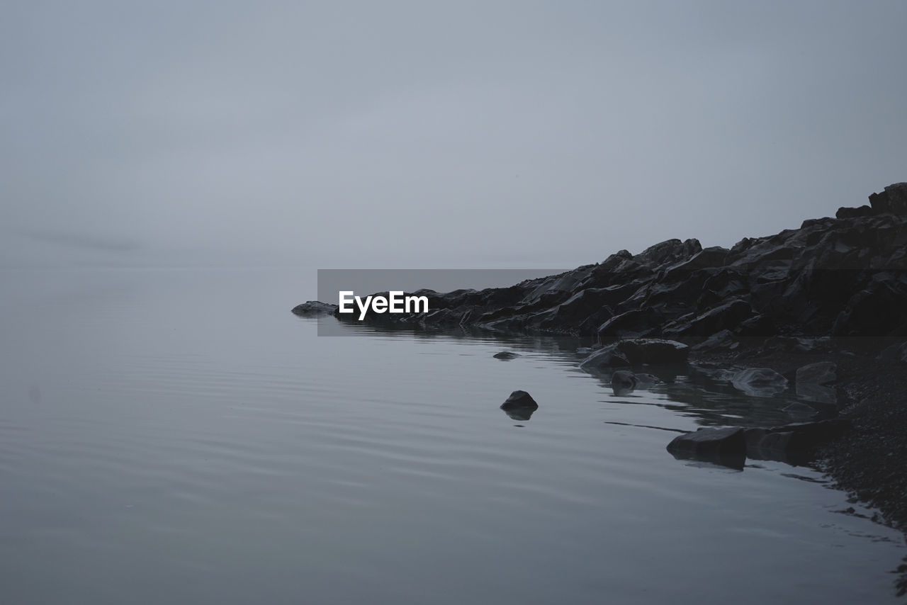 SCENIC VIEW OF ROCKS BY SEA AGAINST CLEAR SKY