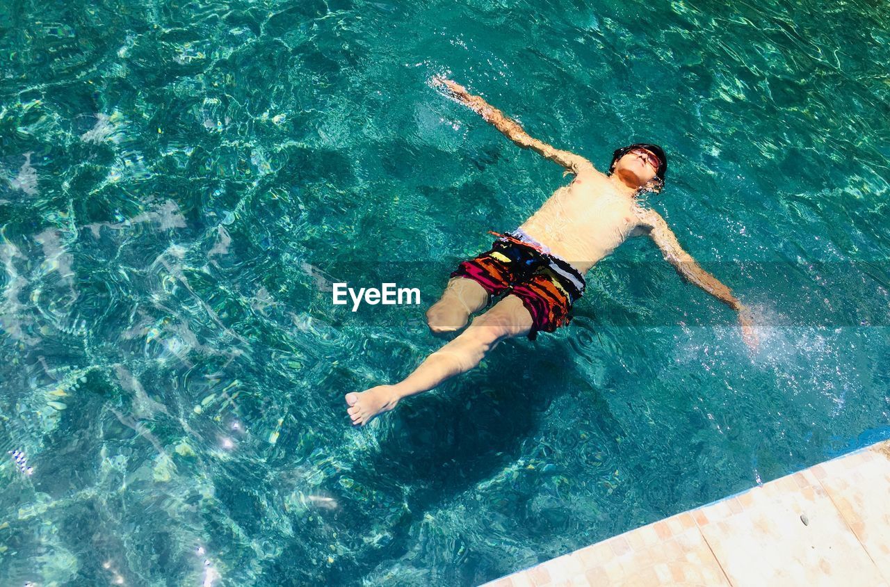 HIGH ANGLE VIEW OF PERSON SWIMMING IN POOL