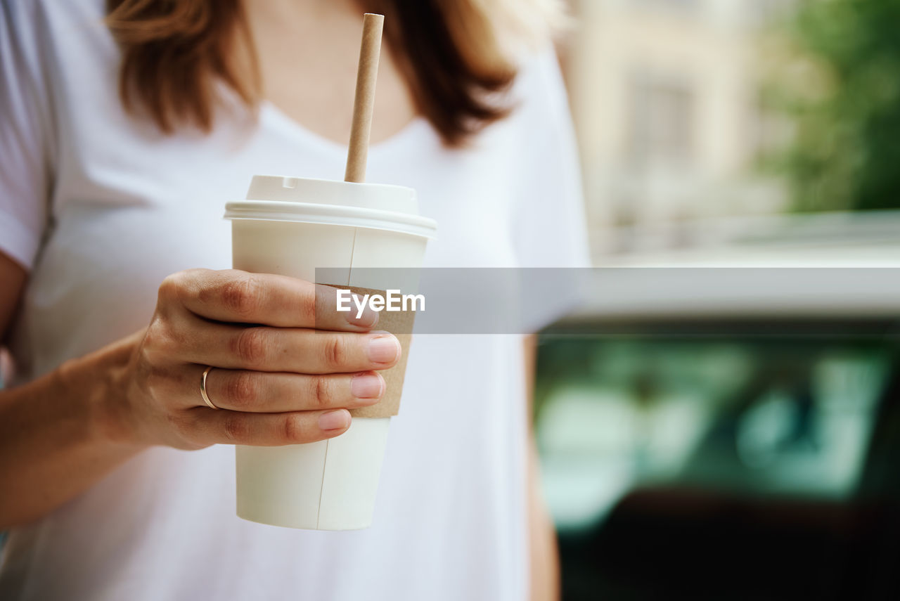 Woman holds paper coffee cup at city street