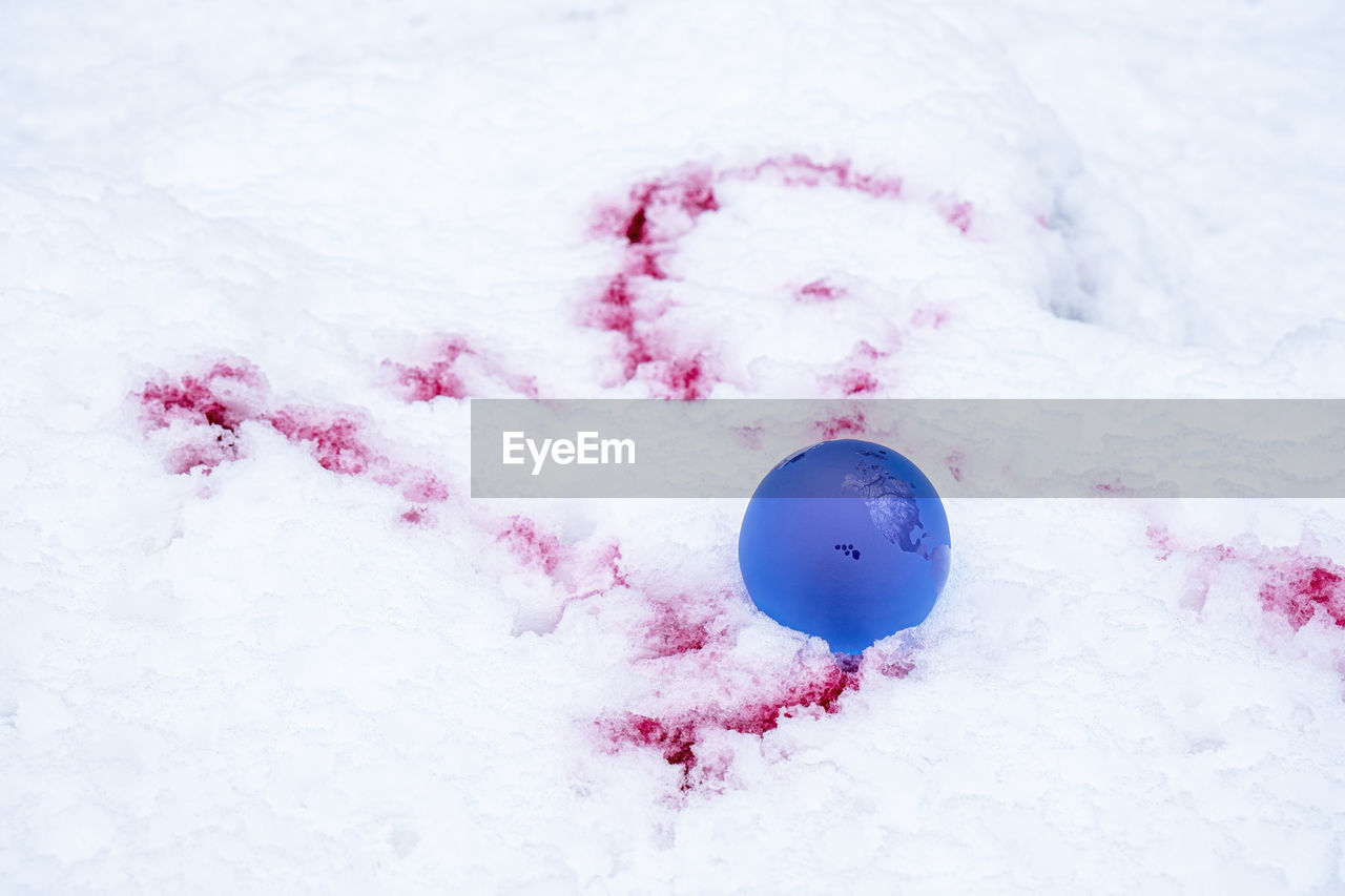 The concept of symbolism. crystal earth globe on snow with blood stains, selective focus