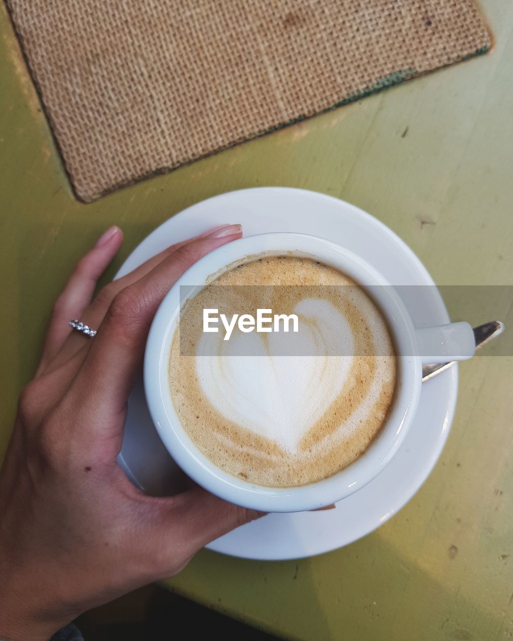 Cropped hand of woman holding coffee cup on table