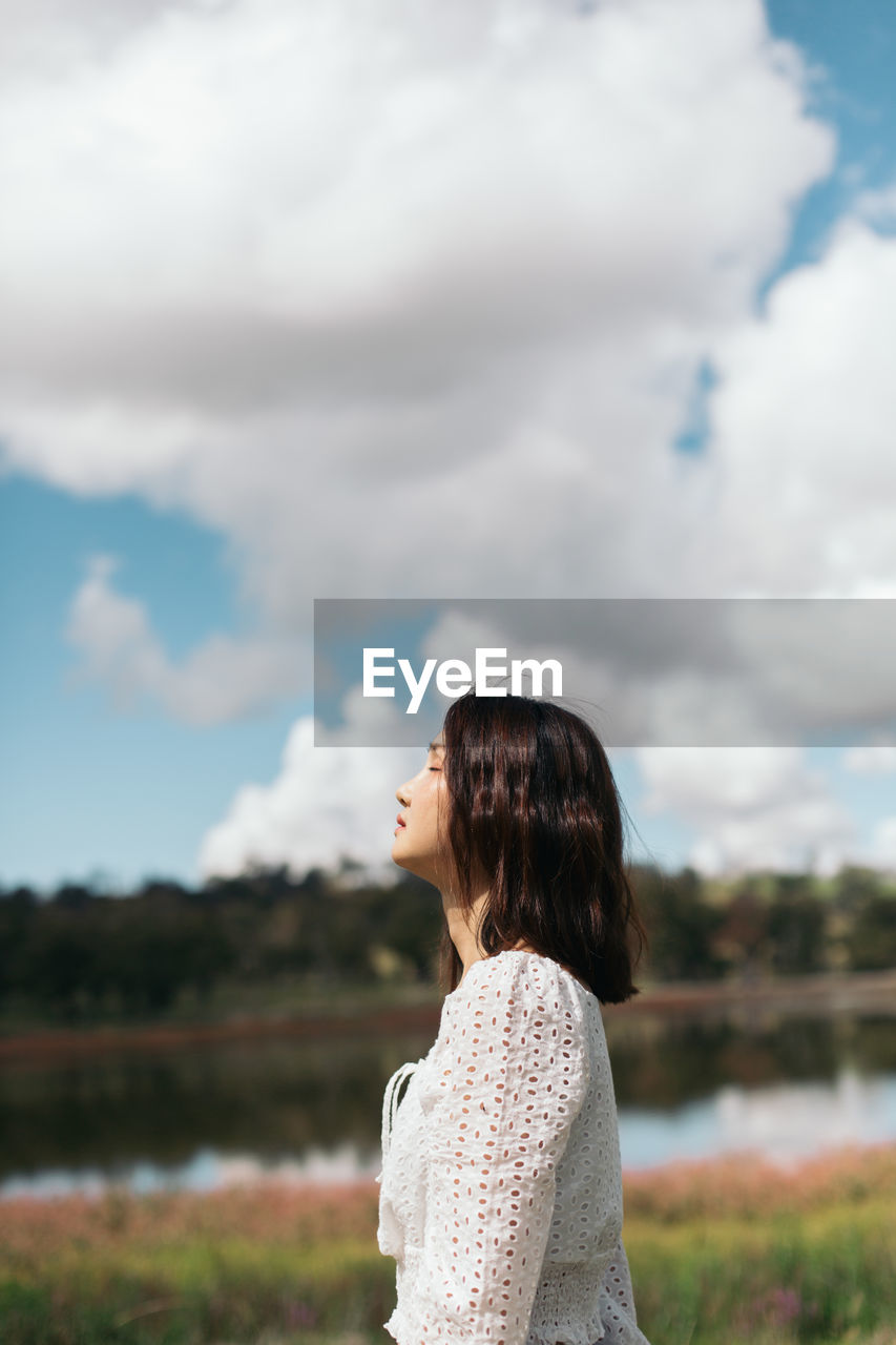 Side view of woman standing against sky