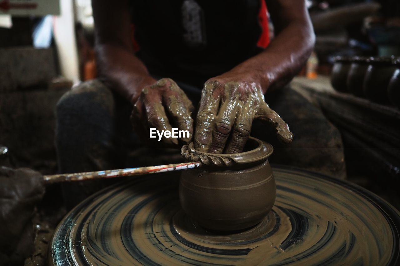 Midsection of man making pottery in workshop