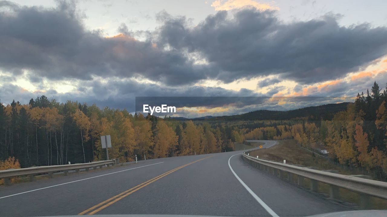 VIEW OF ROAD ALONG TREES AND CLOUDS