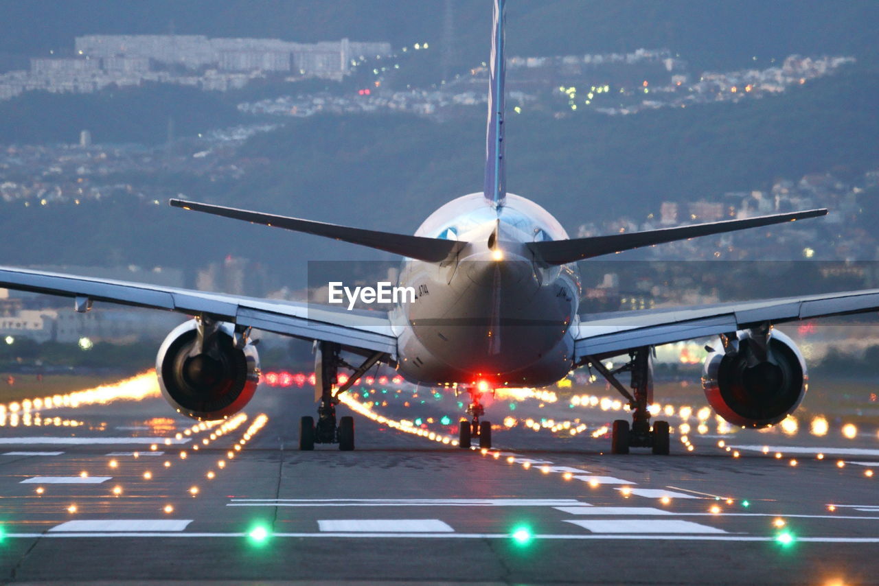 Airplane flying over airport runway against sky