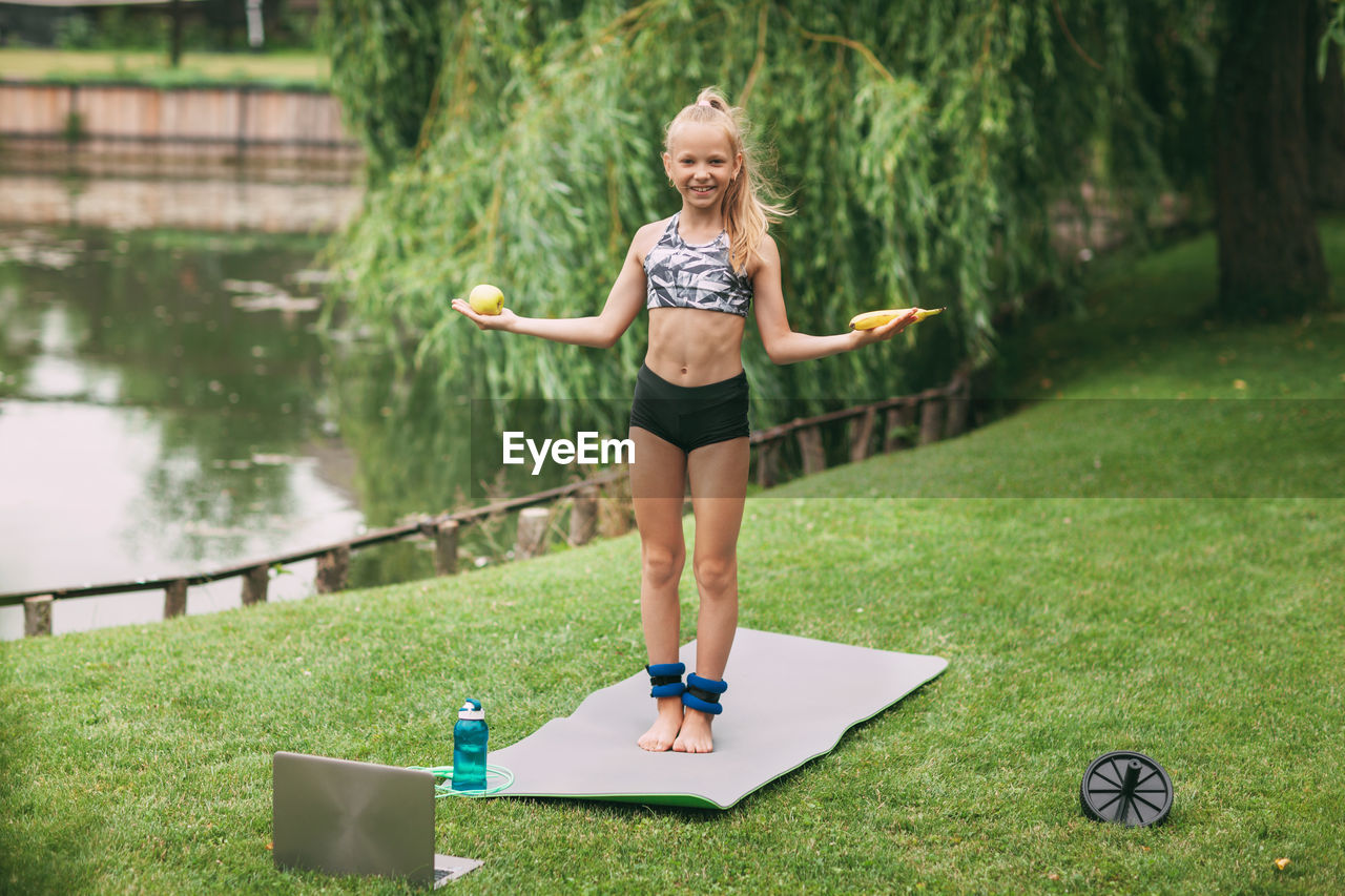 Girl with laptop exercising on field