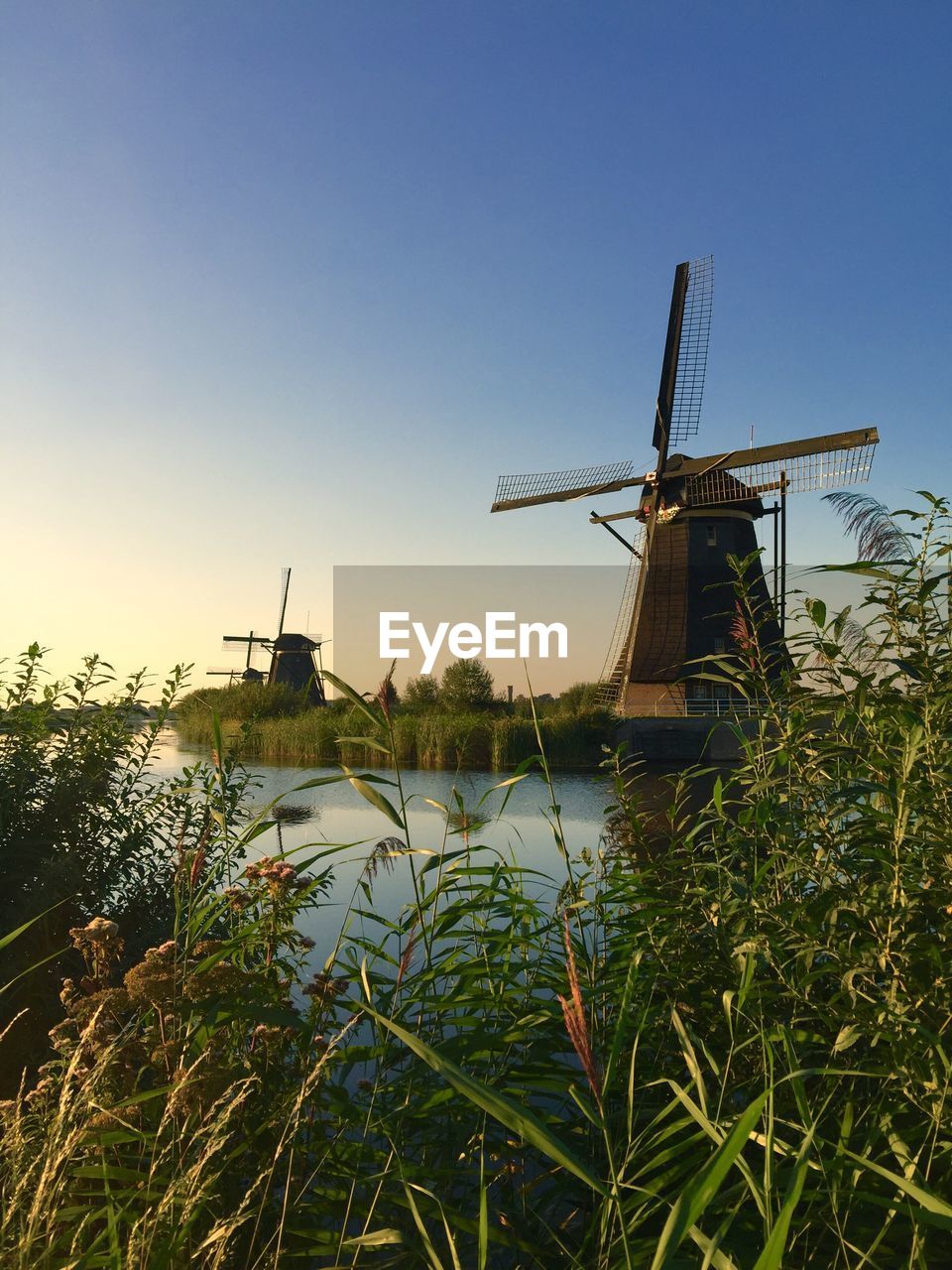 Traditional windmill on field against clear blue sky