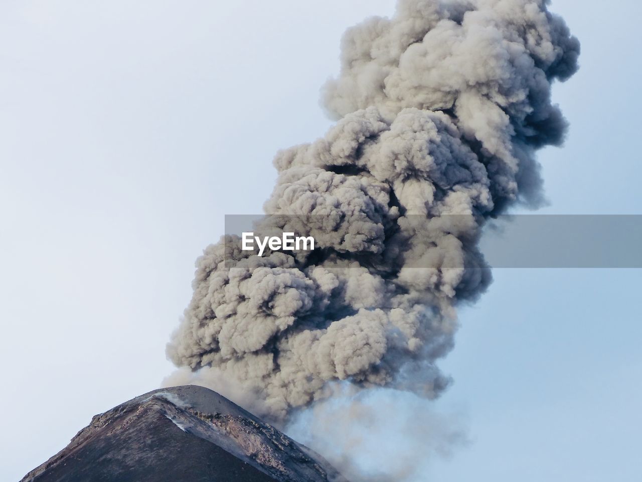 Smoke emitting from volcanic mountain against sky