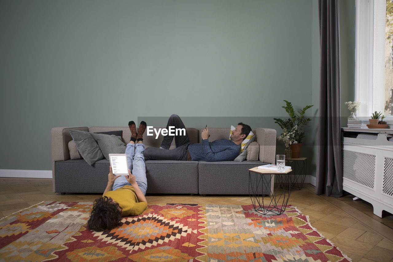 Couple relaxing together in the living room with different electronic devices