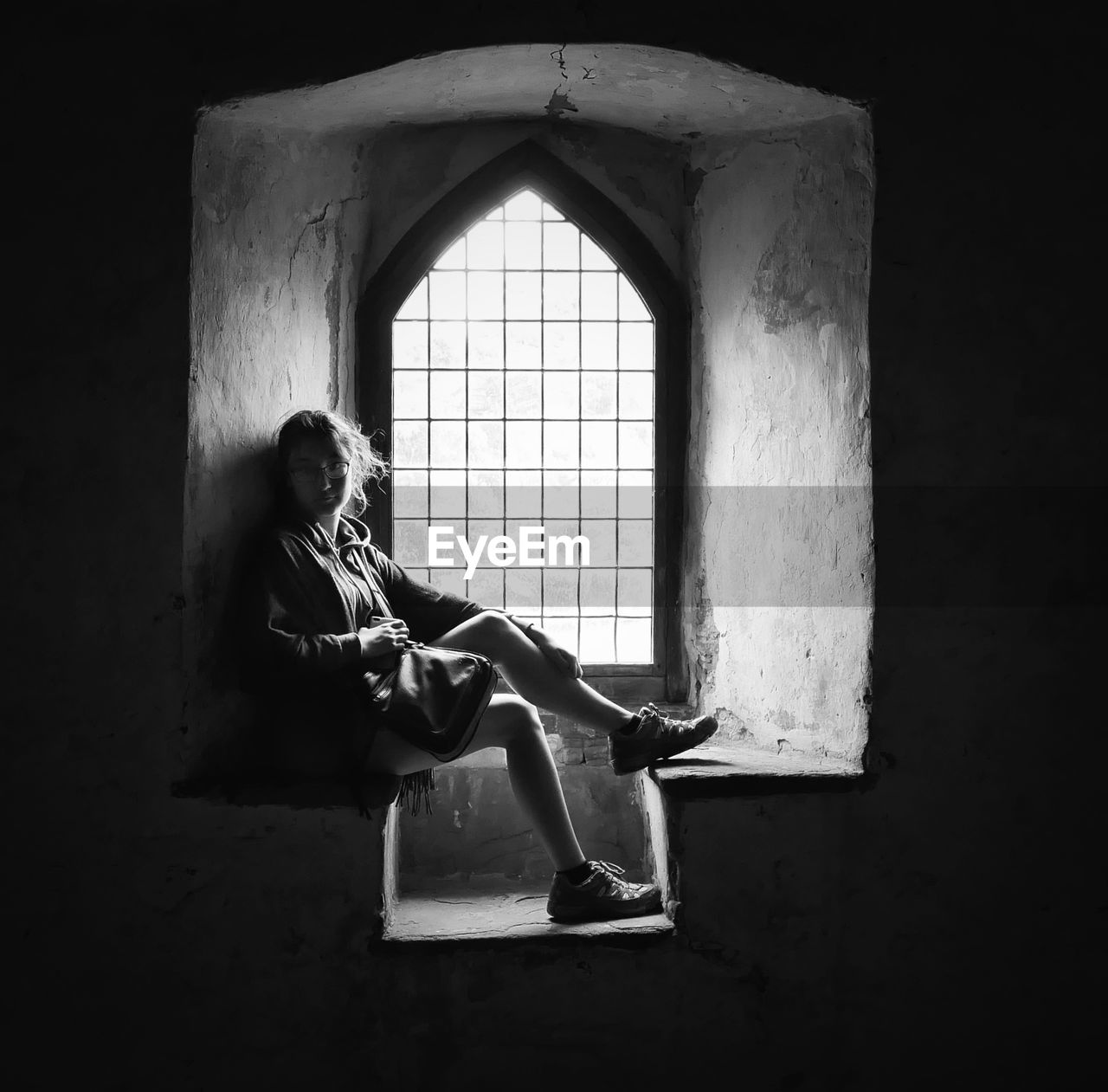 WOMAN SITTING ON WINDOW OF A HOUSE