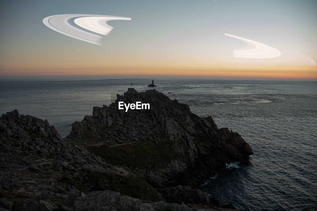 Scenic view of sea against sky during sunset with planet saturn 