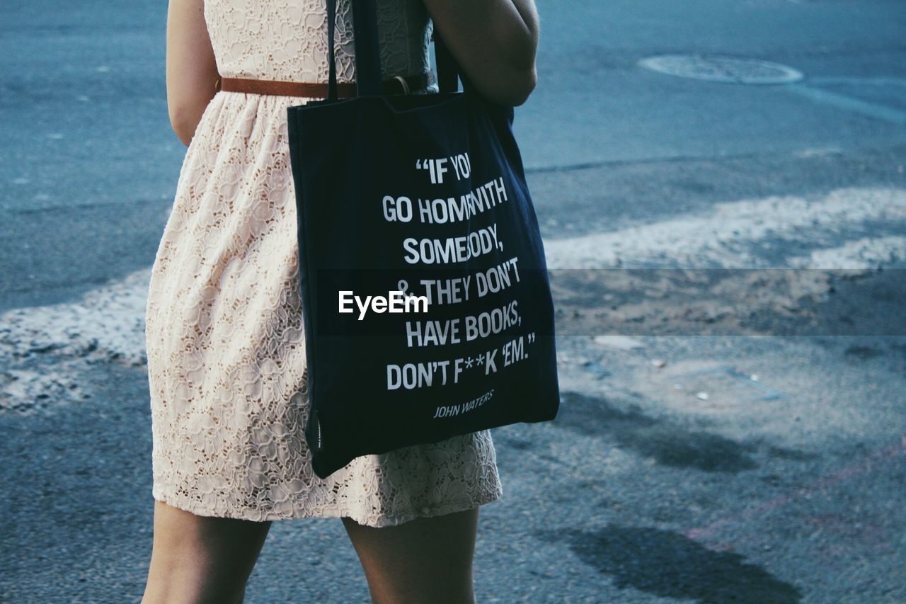 Midsection of woman holding bag with message written on it