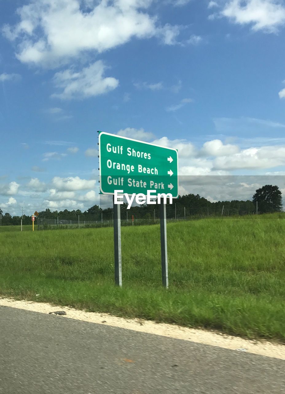 ROAD SIGN ON FIELD AGAINST CLOUDY SKY