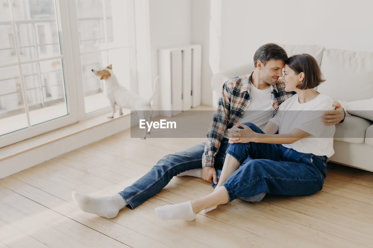 Couple sitting by sofa at home