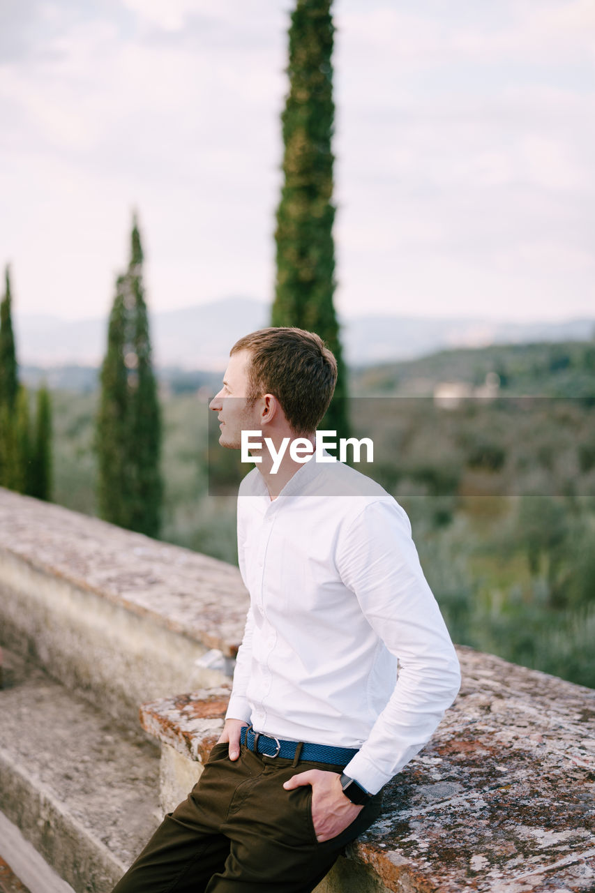 Groom looking away while standing outdoors