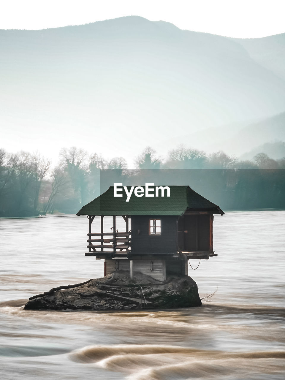 Built structure by lake and mountain against sky