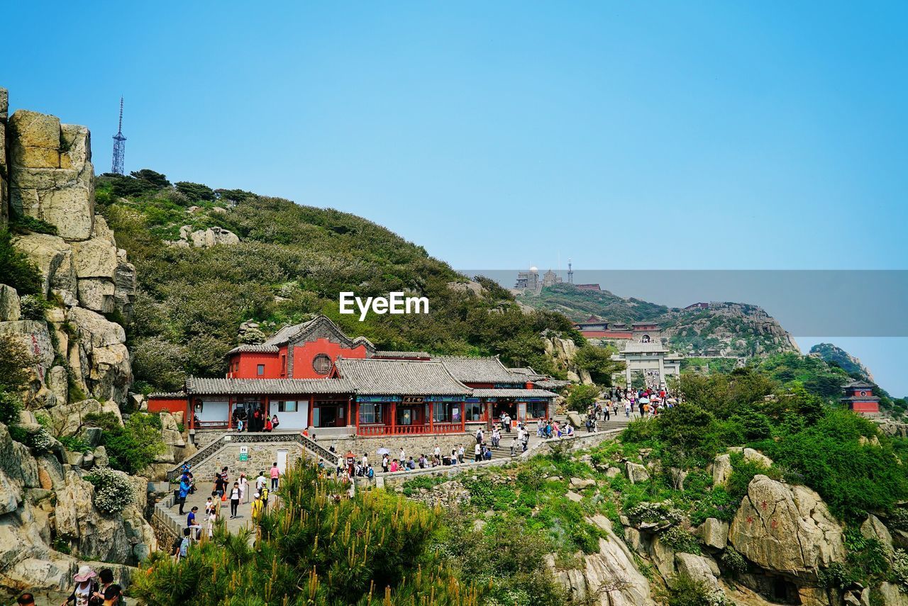 People at temple on mountain against clear sky