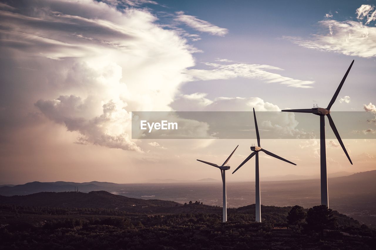 WIND TURBINES ON LAND AGAINST SKY