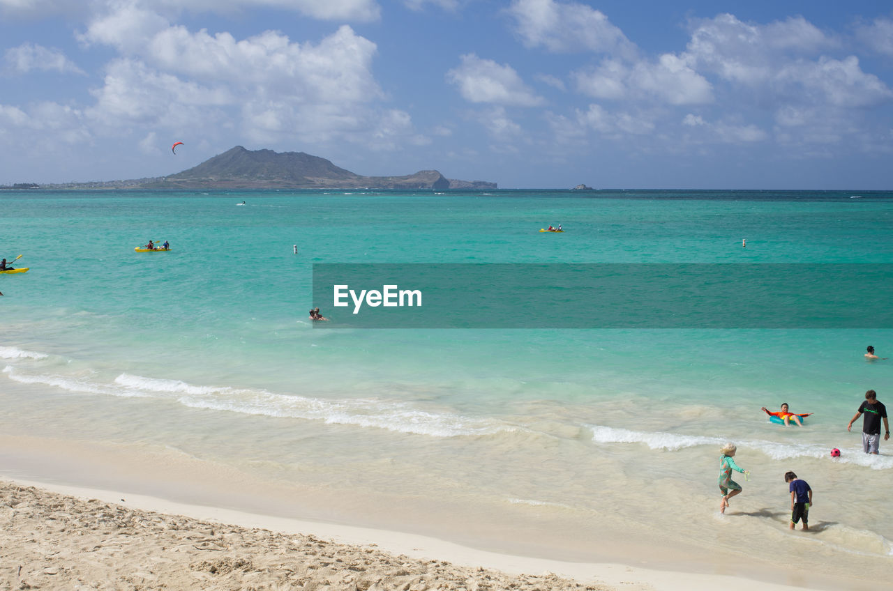 PEOPLE ENJOYING ON BEACH AGAINST SKY