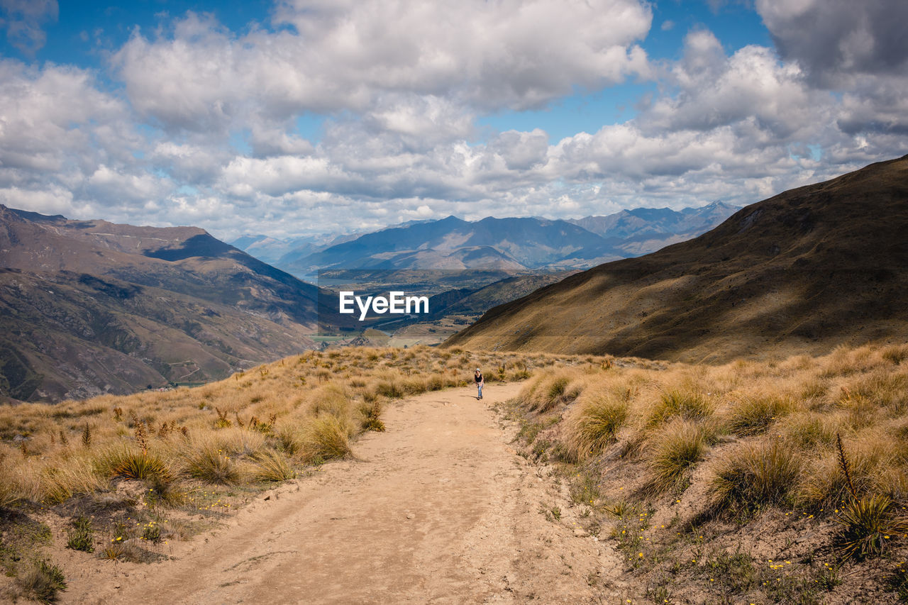 Dirt road amidst landscape against sky