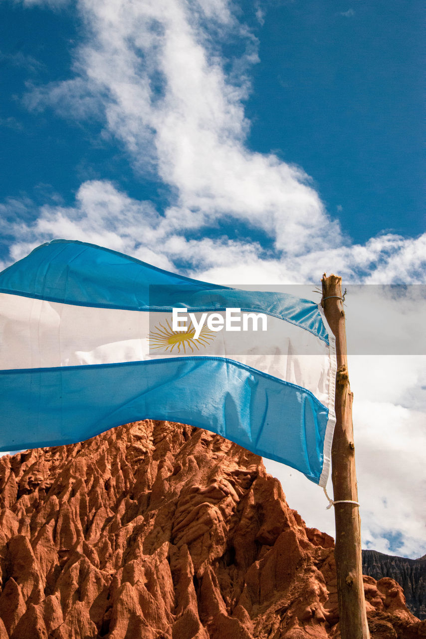 Low angle view of flag on mountain against sky