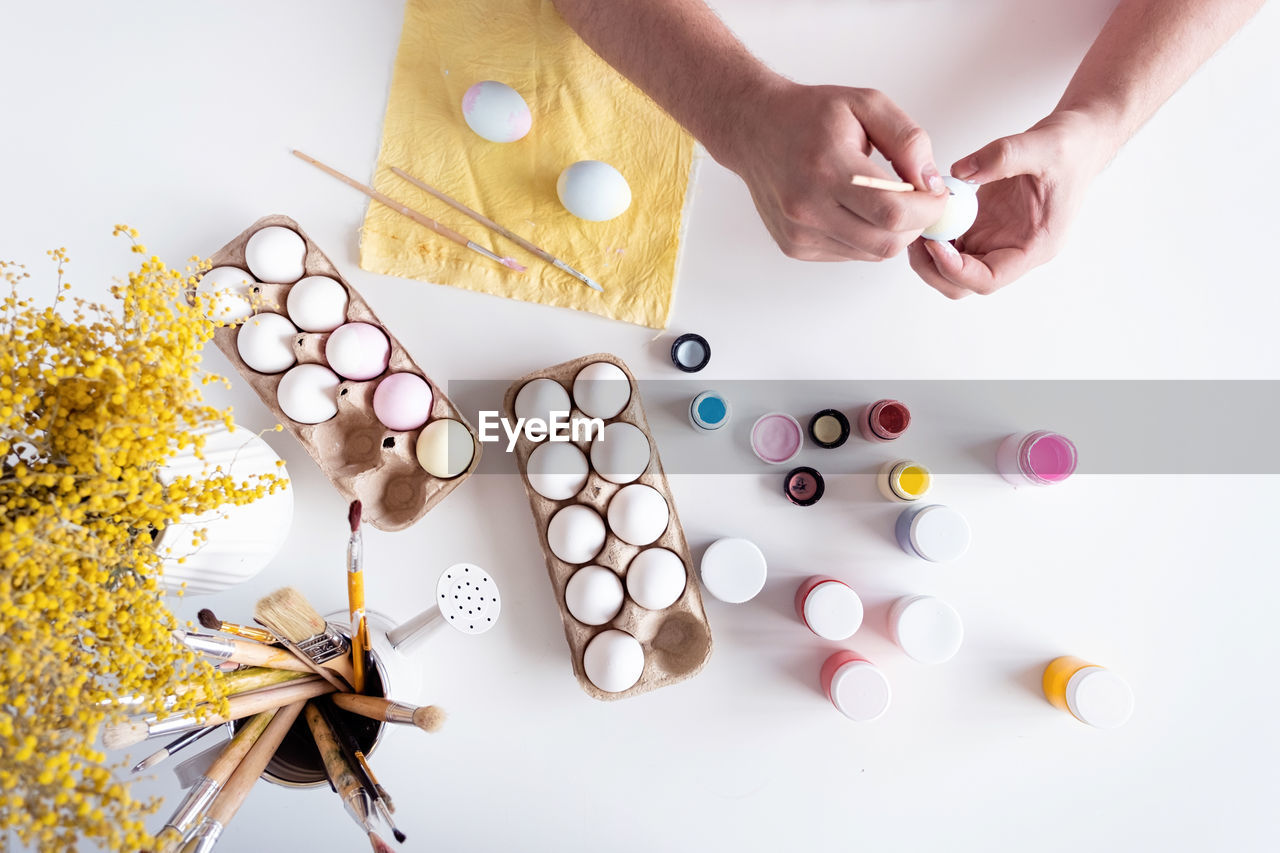 Man coloring easter eggs at home kitchen