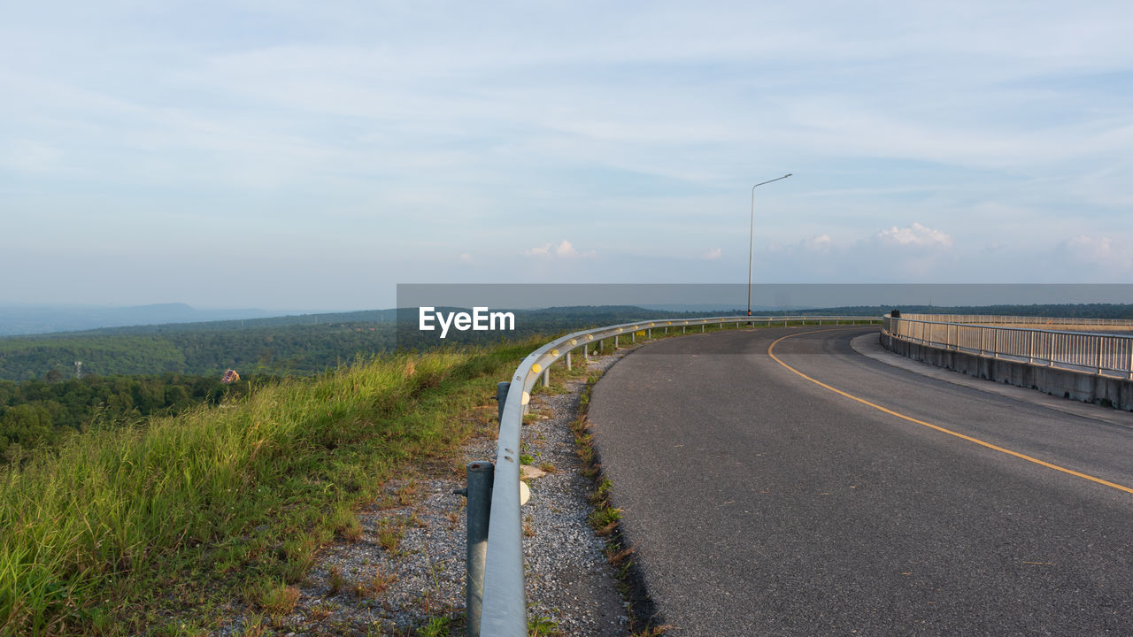 Empty road amidst field against sky