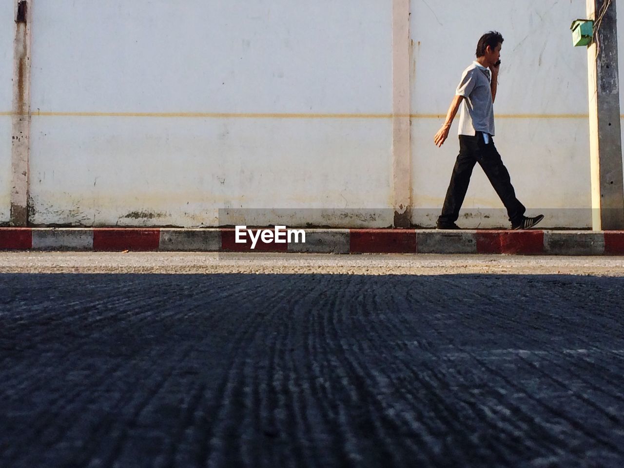 Man talking on mobile phone while walking on sidewalk