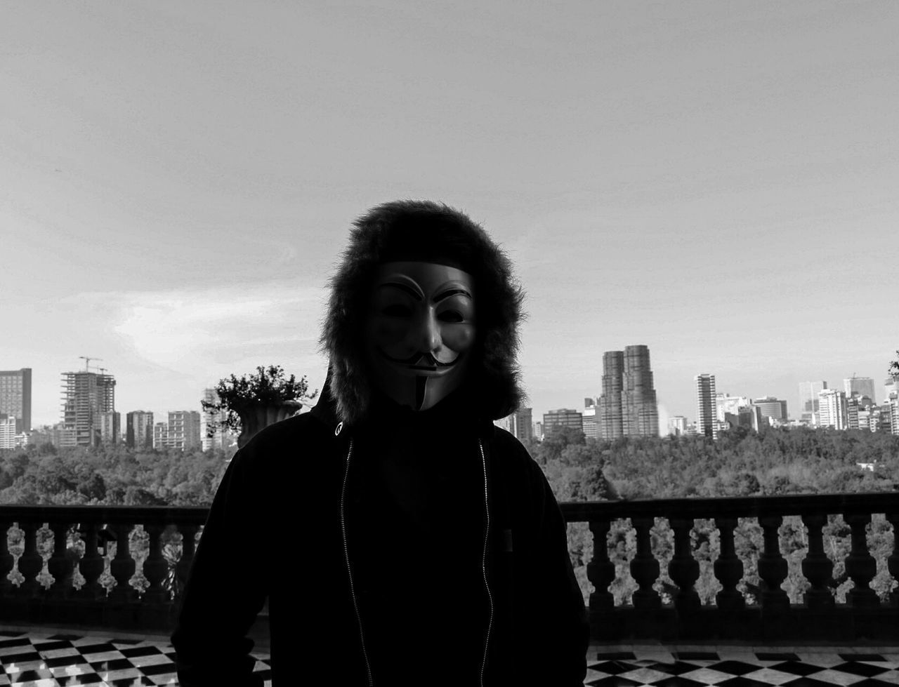 PORTRAIT OF SMILING YOUNG WOMAN STANDING BY RAILING AGAINST SKY