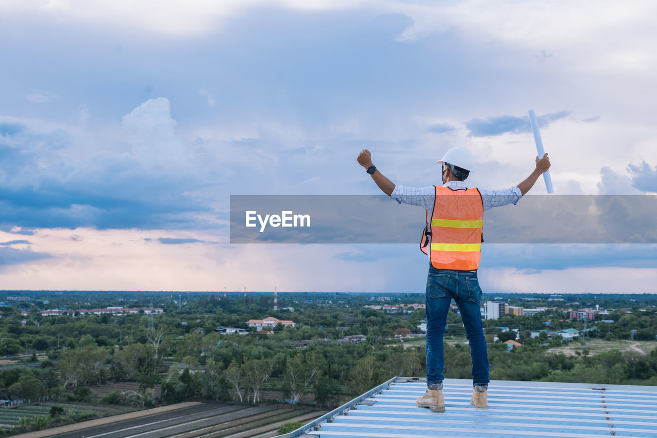 Rear view of man standing at observation point against sky