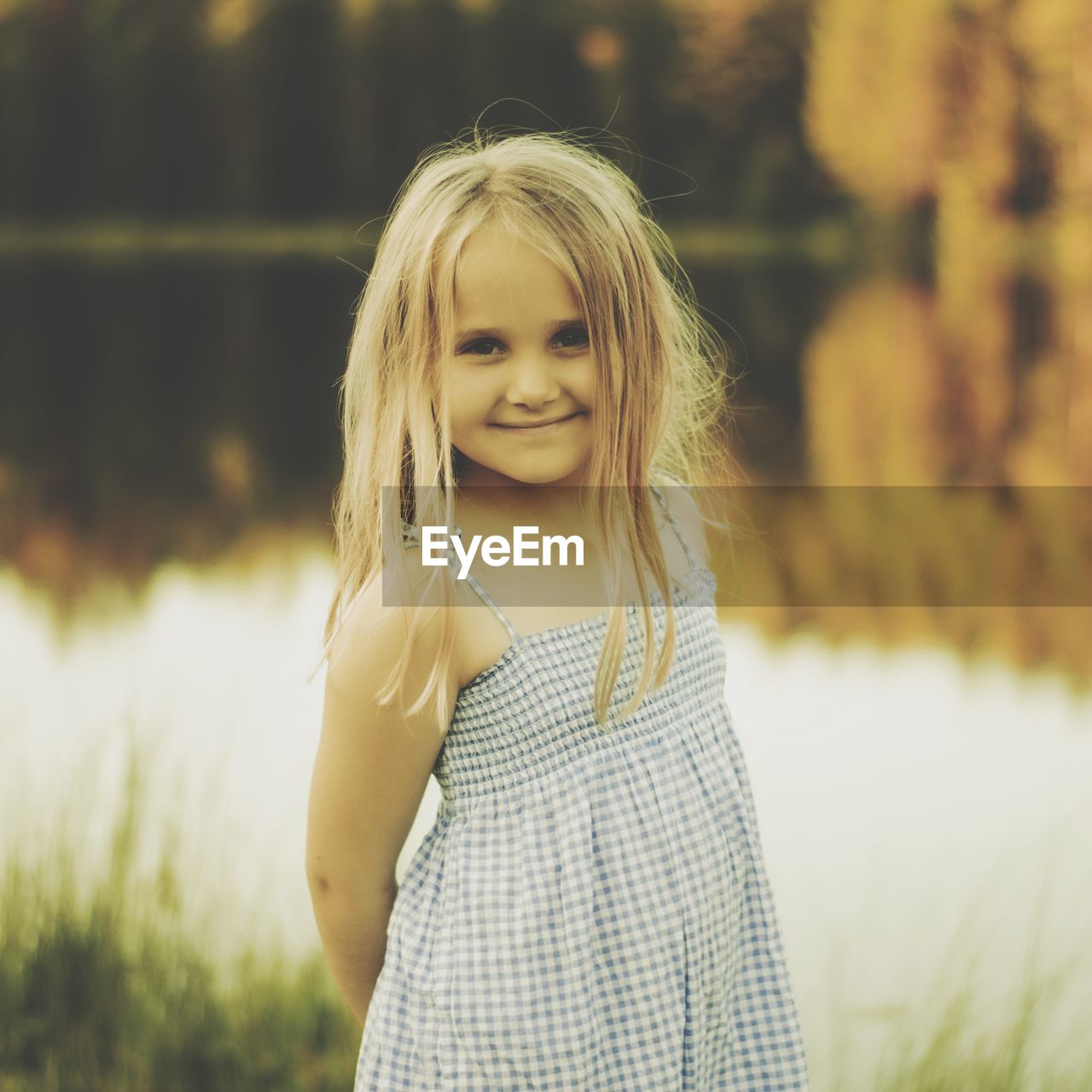 Portrait of smiling girl standing against lake