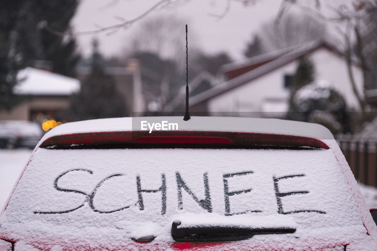 Text on snow covered car rear windshield during winter