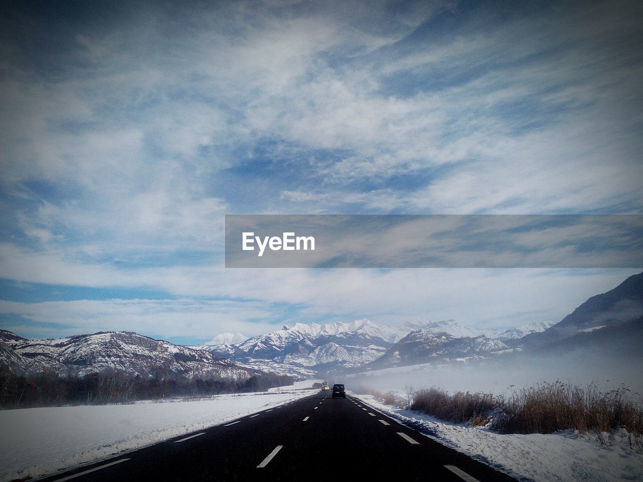 Road amidst snowcapped mountains against sky