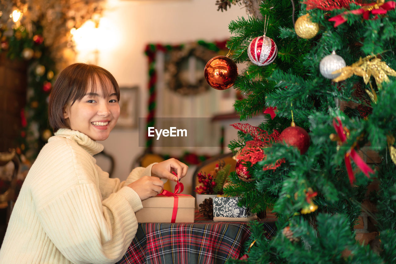 Portrait of young smiling woman holding gift box